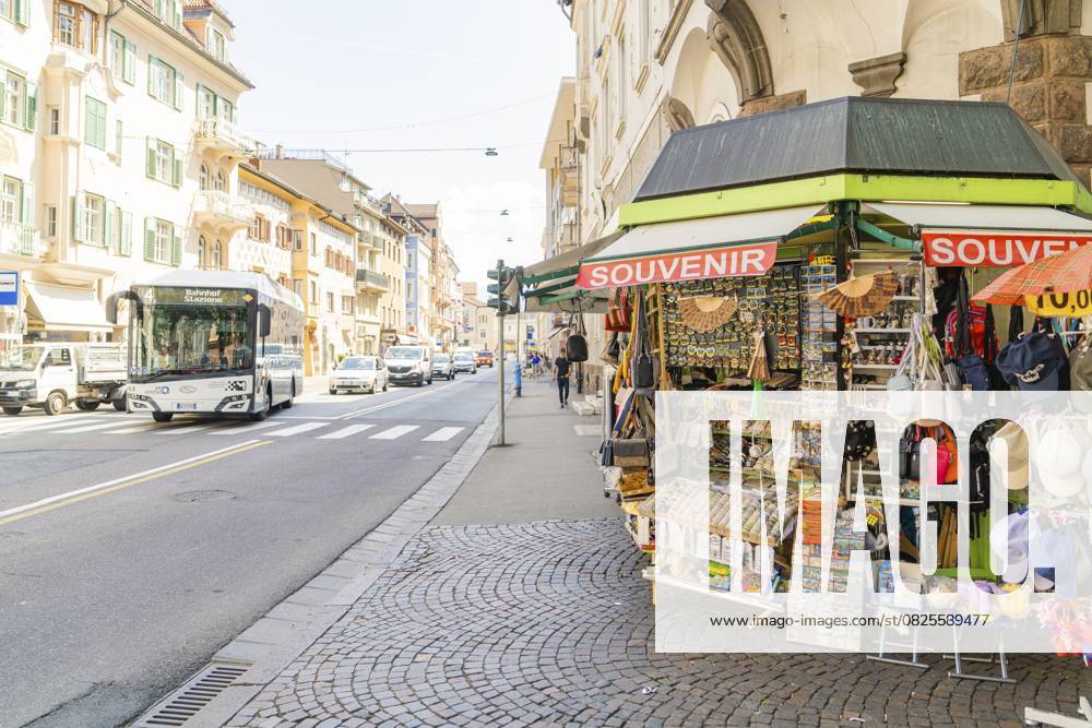 Ein Souvenirstand steht am Bürgersteig in der Nähe einer belebten Straße mit vorbeifahrendem Bus, Meran, Südtirol, Italien, Europa A souvenir stand on the pavement near a busy street with a passing bus, Merano, South Tyrol, Italy, Europe