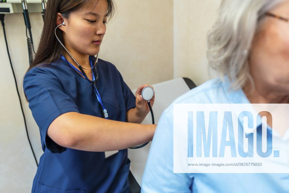 Ärztin mit Stethoskop bei der Untersuchung der Lunge eines älteren Patienten während einer medizinischen Untersuchung im Krankenhauszimmer Female doctor using stethoscope examining lungs of senior patient during medical checkup in hospital room