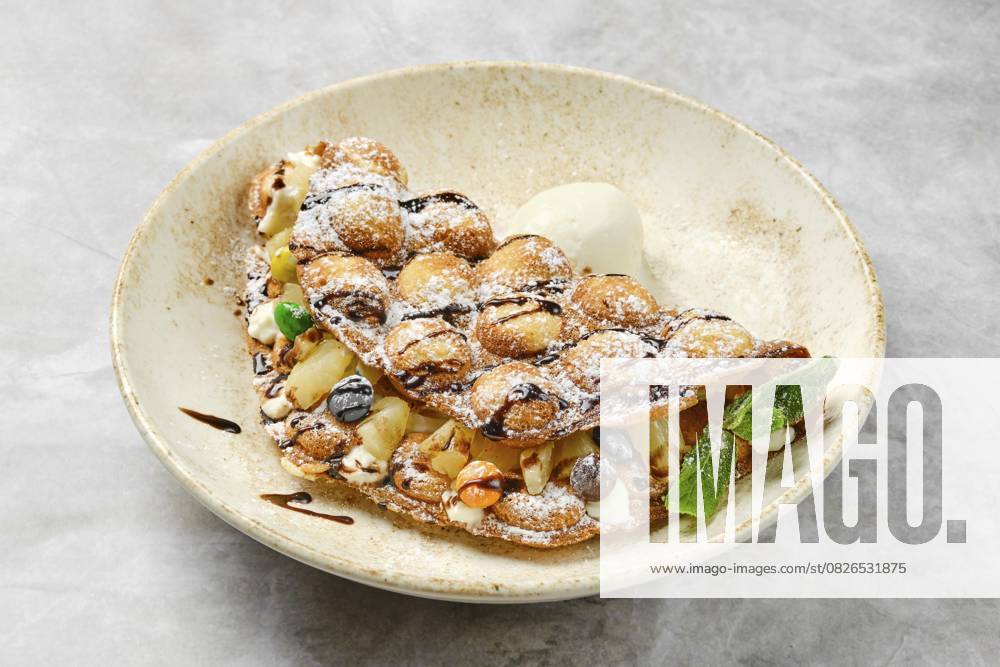 Ein köstliches Dessert mit einer fluffigen, goldbraunen Waffel, gefüllt mit verschiedenen frischen Früchten, Sahne und Schokoladenraspeln. Sie sitzt elegant in einer rustikalen Schale und lädt zum Genießen ein A mouthwatering dessert showcases a fluffy, golden-brown waffle filled with a variety of fresh fruits, cream, and drizzled chocolate. It sits elegantly in a rustic bowl, inviting indulgence