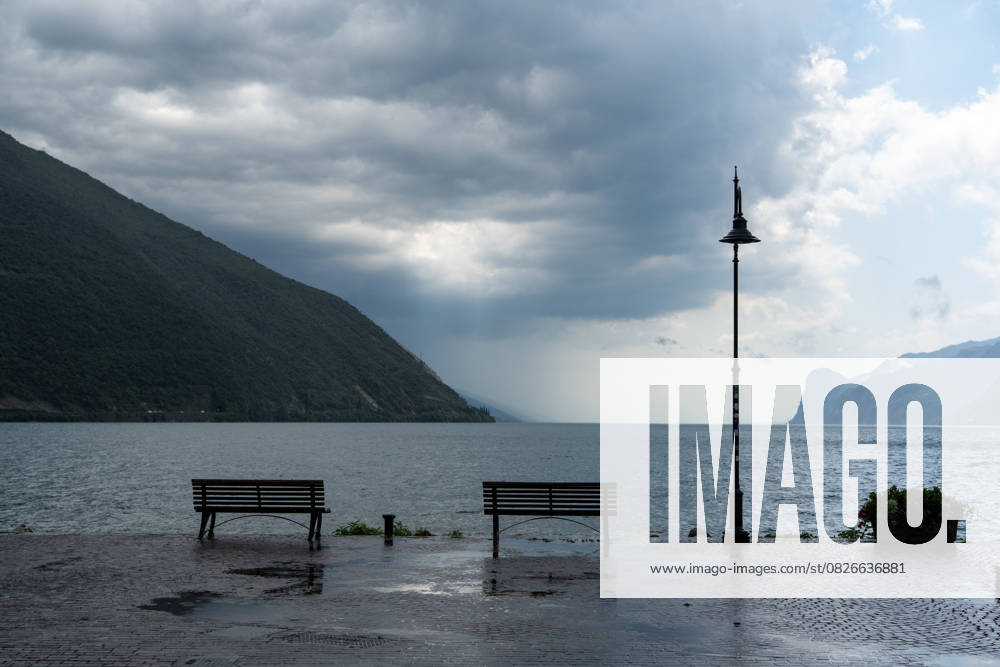 Storm on Lake Garda with extreme rainfall and thunderstorms. Storm clouds and empty benches on the northern shore of Lake Garda