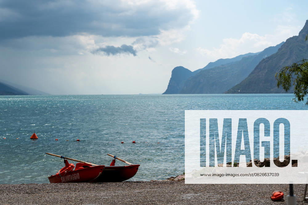 Storm on Lake Garda with extreme rainfall and thunderstorms. Lifeboat on an empty beach in front of storm clouds