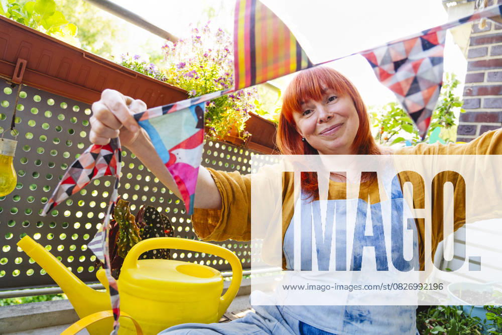 IMAGO Creative, Lifestyle, Feste im Garten #2 Smiling person decorates garden with bunting for joyful celebration at home model released, Symbolfoto property released, IHF02238