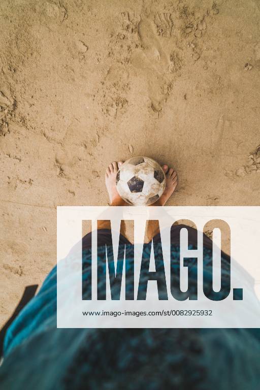 Low section of man with footall on the beach model released Symbolfoto KKAF00899