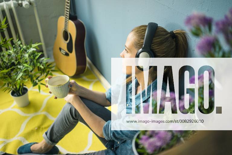 Beautiful woman in her home, decorated with plants, listening music with headphones model released Symbolfoto property released MOEF00882