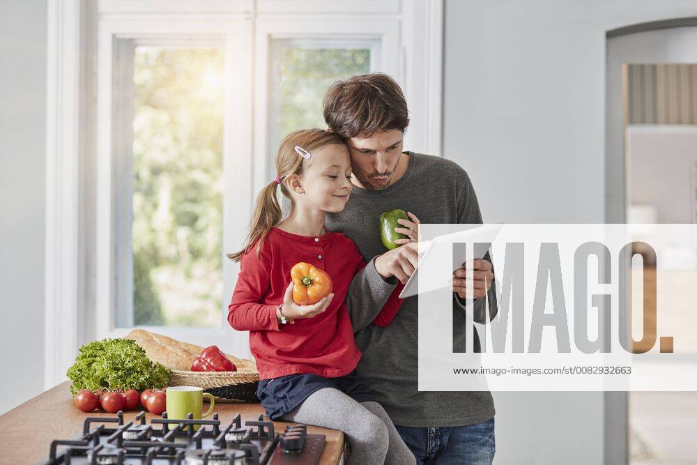 Father and daughter with bell pepper and tablet in kitchen model released Symbolfoto property released RORF01136