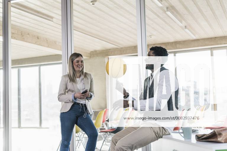 Woman looking at businessman balancing basketball in office model released Symbolfoto property released UUF13118