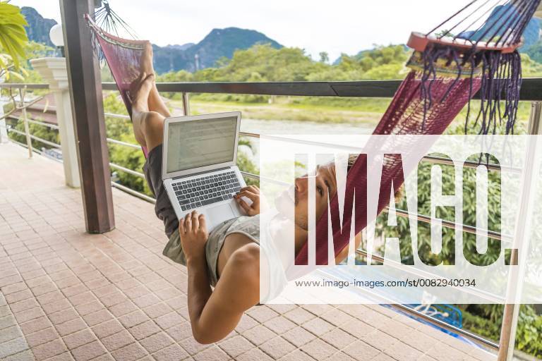 Laos, Vang Vieng, young man lying in hammock using laptop model released Symbolfoto AFVF00297