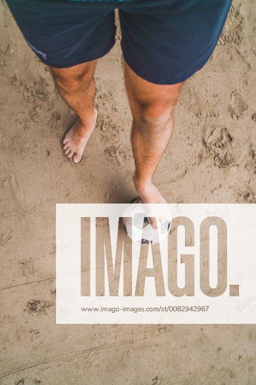 Low section of man with footall on the beach model released Symbolfoto KKAF00898