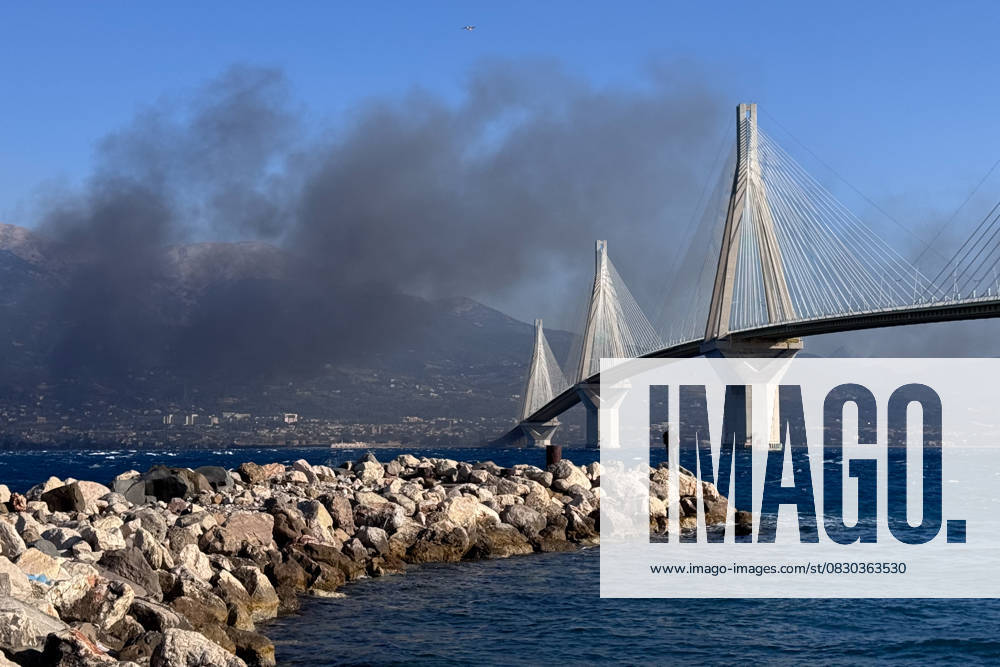 Wildfire Smoke Over The Iconic Rio-Antirrio Bridge. Wildfire smoke rises behind the iconic Rio-Antirrio Bridge near the city of Patras, Greece. Antirrio West Greece Greece