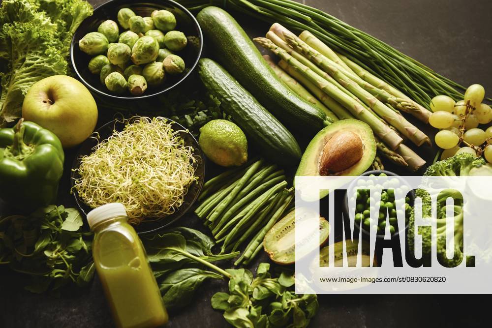 Grüne gesunde Lebensmittel Zusammensetzung mit Avocado, Brokkoli, Apfel Smoothie cucomber Spargel Kiwi Bohne. Platziert auf dunklem Hintergrund. Ansicht von oben Green healthy food composition with avocado, broccoli, apple smoothie cucomber asparagus kiwi bean. Placed on dark background. Top view