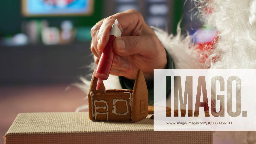 IMAGO Creative, Weihnachten, Food, Backen, Lebkuchen Father Christmas decorates homemade gingerbread house with frosting Father Christmas decorates homemade gingerbread house with frosting and beads, North Pole log cabin workshop. Santa keeping the festive tradition of baking sweet treats with cinnamon. Camera A., model released, , property released, , 63271680.jpg RECORD DATE NOT STATED