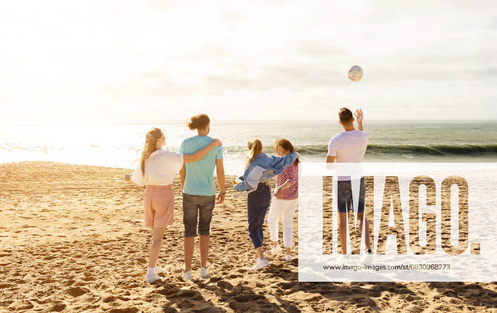 Friends enjoying a sunny day at the beach while playing with a ball A group of five friends stands on the sandy beach, enjoying a sunny day. They are playing with a ball and laughing as the waves crash gently behind them., model released, , 63323714.jpg RECORD DATE NOT STATED