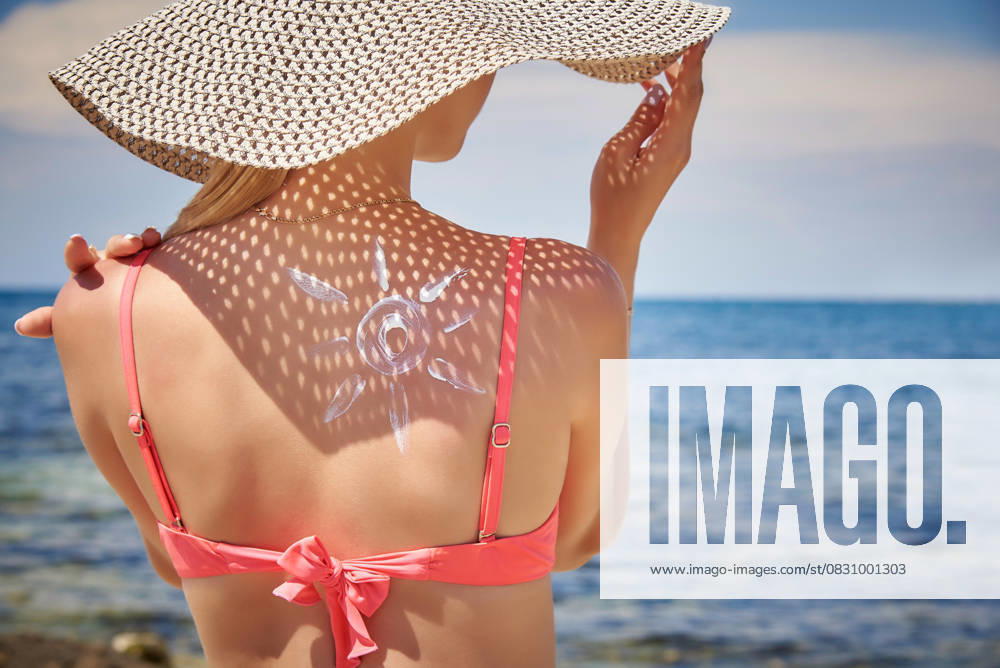 Frau entspannt am Strand mit Sonnenhut und Sonnenmuster auf dem Rücken, genießt den Sommertag am Meer Frau entspannt am Strand mit Sonnenhut und Sonnenmuster auf dem Rücken, genießt den Sommertag am Meer (License=RF) ,model released, Symbolfoto