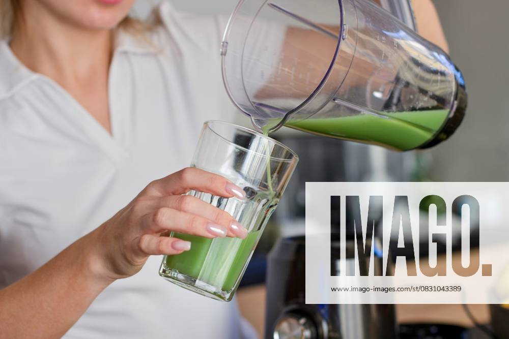 A girl in a white T-shirt pours a green smoothie into a glass. A girl in a white T-shirt pours a green smoothie into a glass. High quality photo, model released, , 63577006.jpg RECORD DATE NOT STATED