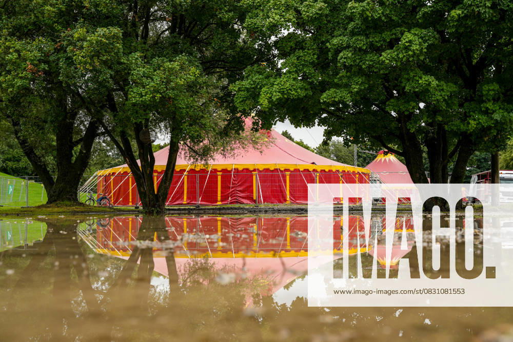 IMAGO Creative, Jahreszeit Sommer, Regen, Sommerregen Rotes Zirkuszelt, das sich im Wasser spiegelt Großes, rotes Zirkuszelt inmitten einer Überschwemmung aufgrund von starkem Regen. Das Wasser spiegelt das Zelt und die umliegenden Bäume wider (License=RF)