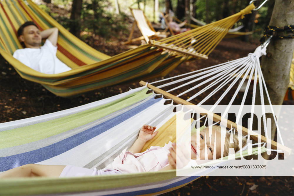 Smiling girl relaxing in hammock with man outdoors in forest model released, Symbolfoto, NSTF00556