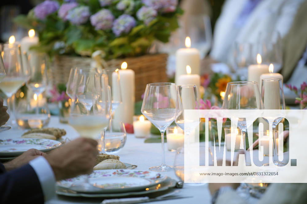 IMAGO Creative, Lifestyle, Feste im Garten #2 Guests enjoying a fancy dinner party with candles and wine glasses Elegant outdoor dinner party with candles illuminating the table and wine glasses ready for a toast Model Released DondykRiga_ID30951_1050467_002