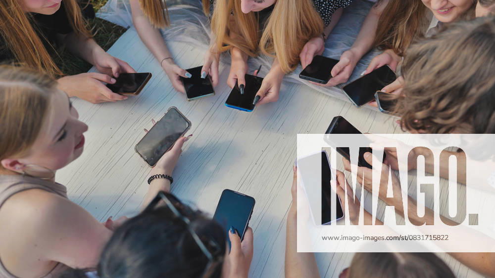 Group of teenagers lying on grass using smartphones together around white table. Group of teenagers lying on grass using smartphones together around white table, model released, , 63354076.jpg RECORD DATE NOT STATED