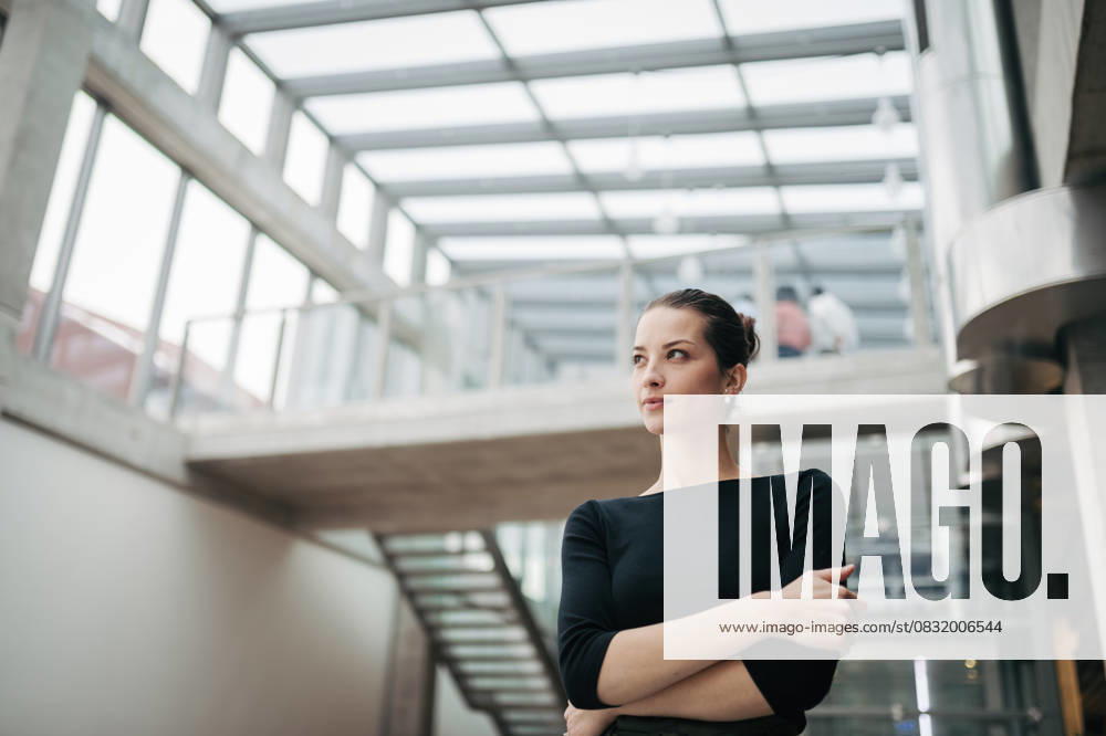 Portrait of young businesswoman standing in modern openspace office building. Portrait of young businesswoman standing in modern openspace office building. Low angle view. model released