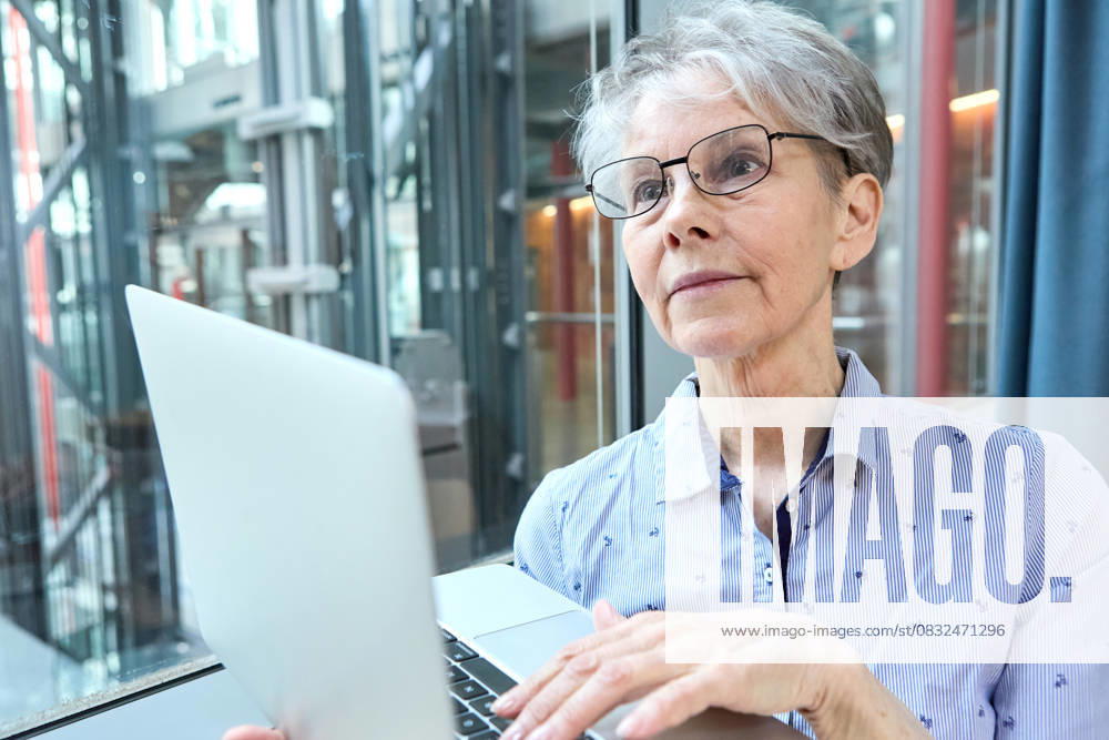 An experienced senior citizen works intently on her laptop at the company. The image shows how active retirement and working until 70 open up new opportunities in retirement.