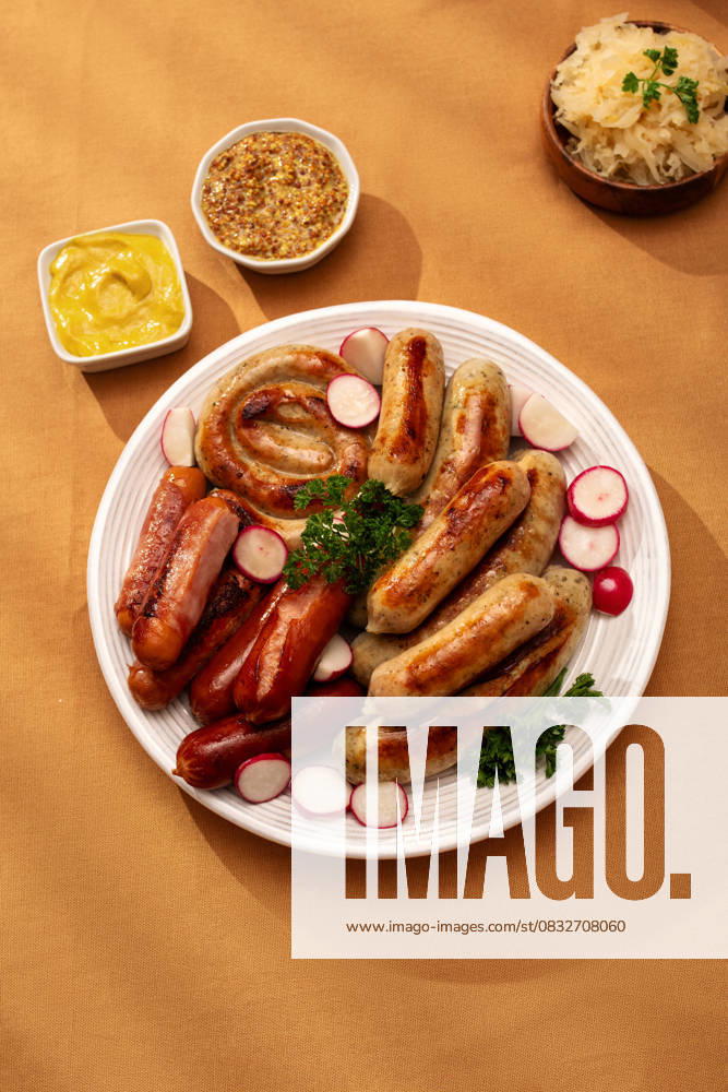Traditional German sausage platter with sauerkraut Top view of a traditional German platter featuring assorted grilled sausages including Bratwurst and Frankfurters, served with tangy sauerkraut and mustard on an autumn table. Model Released MariaShchipakina_ID30874_1046500_008