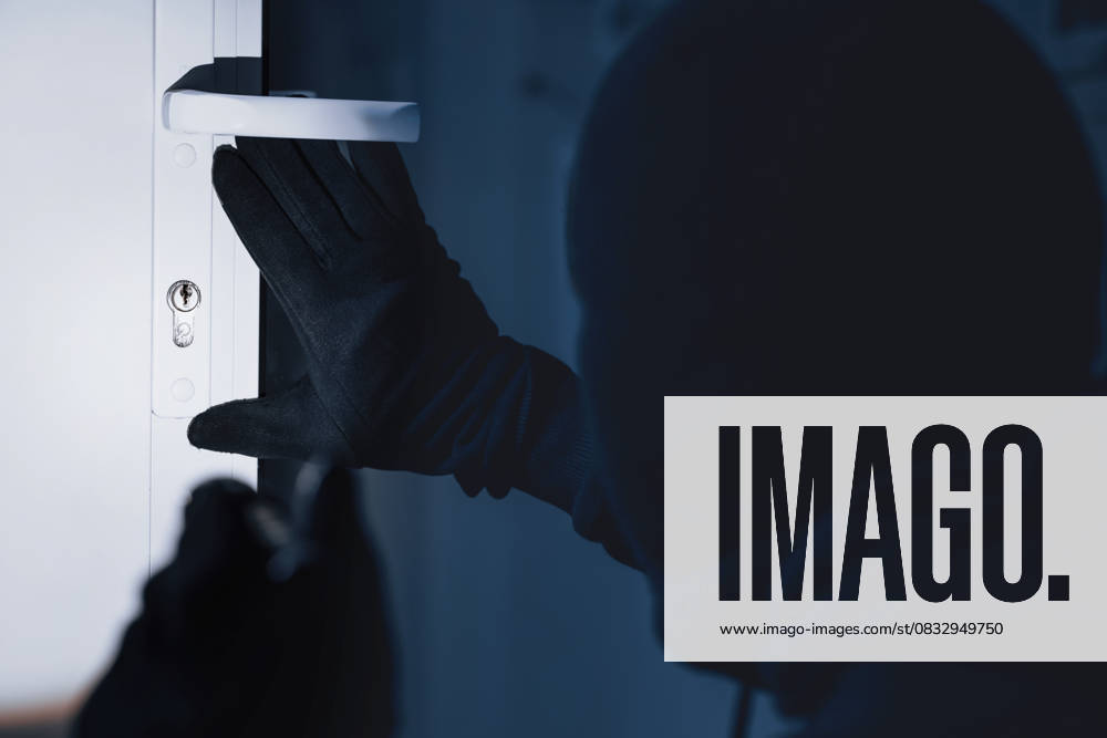 Robber in black balaclava cracking door with metal picklock Break-In Concept. Back view of unrecognizable criminal in black balaclava entering victim s house, using torch on lock, model released, , 94828706.jpg RECORD DATE NOT STATED