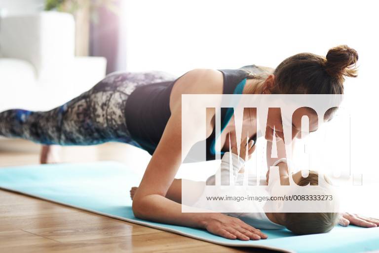 Mother with baby exercising on yoga mat at home model released Symbolfoto property released ABIF00337