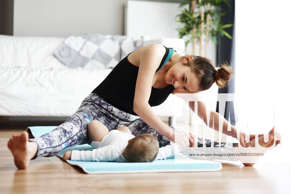 Mother with baby exercising on yoga mat at home model released Symbolfoto property released ABIF00335