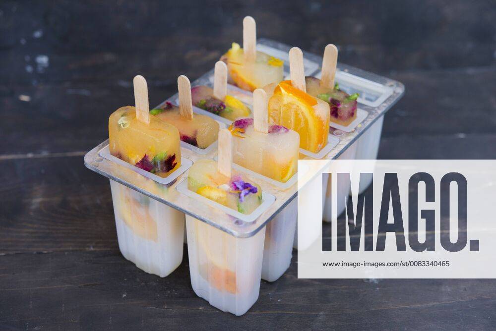 Homemade orange and lemon popsicles with edible flowers SKCF00442