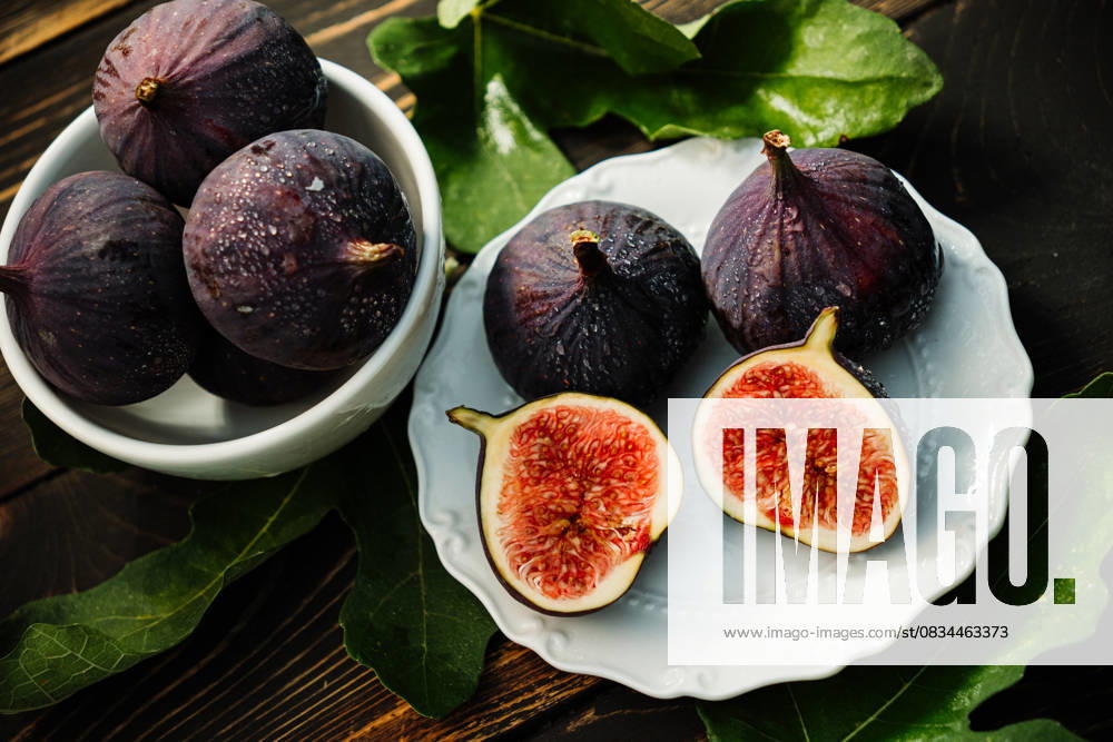 Delicate Fresh Ripe Figs With Leaves On White Plate, Rustic Wooden Table. Ficus Delicate fresh ripe figs with leaves on white plate, rustic wooden table. Ficus carica. Beautiful sweet seasonal fruits, vegan food. Top view. High quality photo, 96035508.jpg RECORD DATE NOT STATED