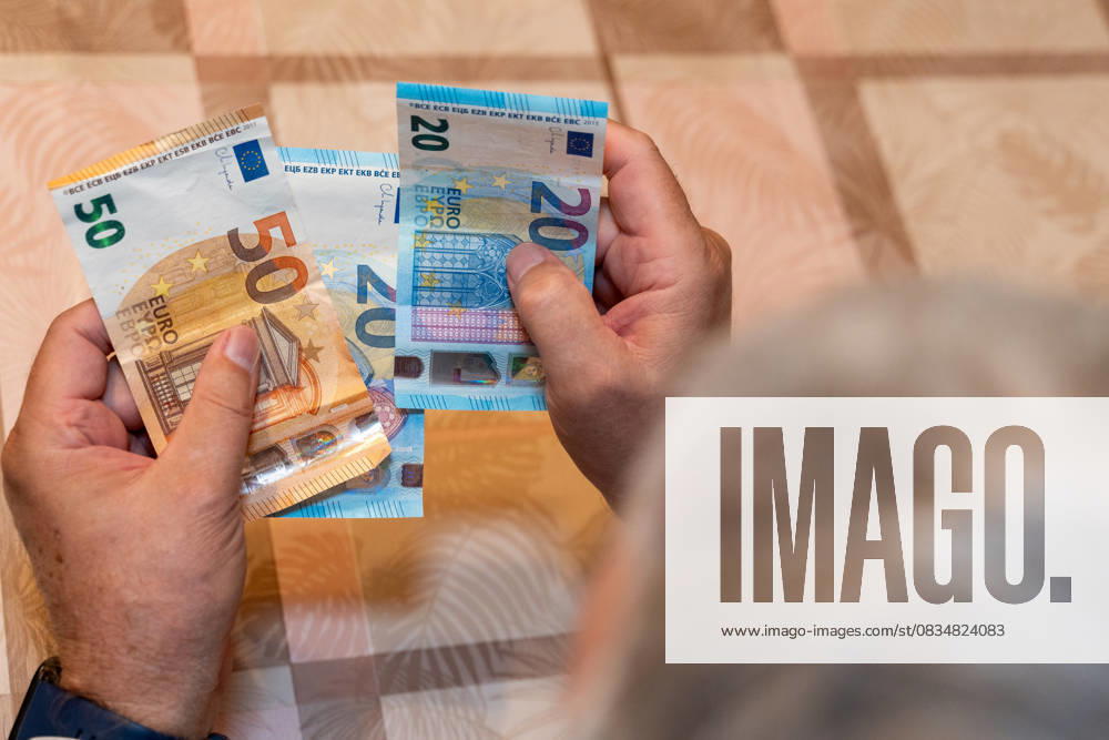 An elderly man holds 50 and 20 euro notes in his hands. The image symbolizes financial security in old age and represents the topics of pensions, retirement provisions, and receiving pension payments.