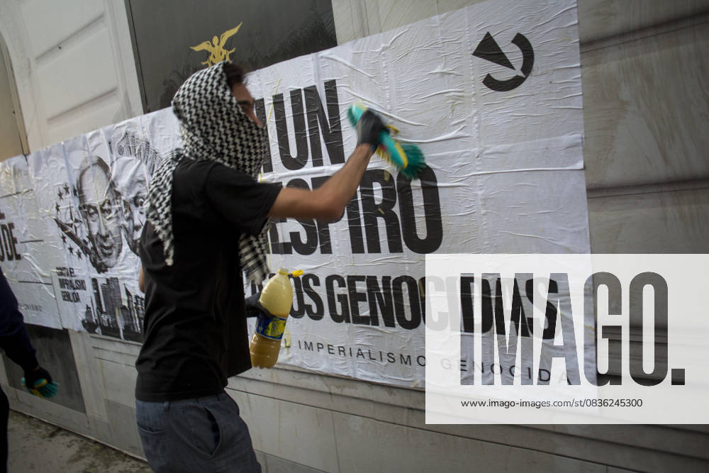 A protester, his face covered by a keffiyeh, pastes a mural.against genocide, during a pro-Palestinian demonstration in central Madrid in solidarity with the Palestinian people in the face of Israeli attacks and condemning the interception by Israeli forces of the Global Sumud Flotilla ships. Madrid Spain - ZUMAs296 20251004_znp_s296_007