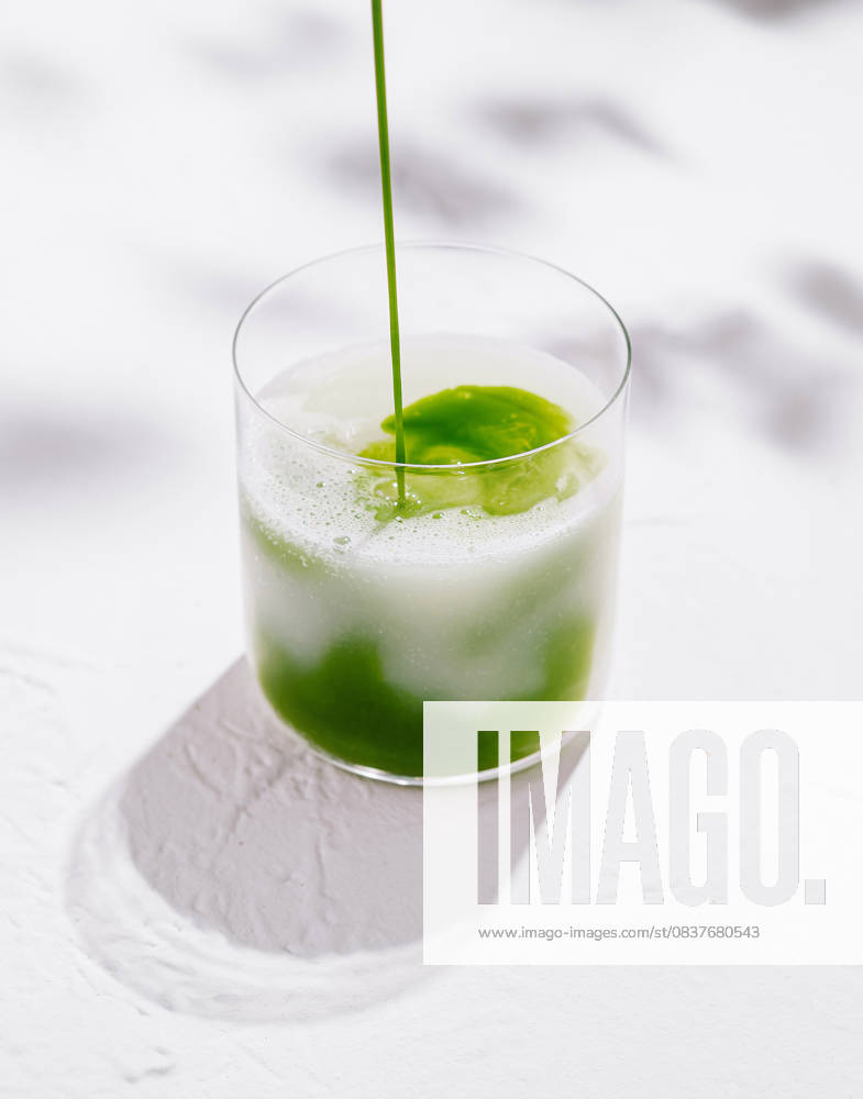 Barista gießt Matcha Latte in Glas auf weißem Hintergrund Barista gießt Matcha Latte in Glas auf weißem Hintergrund (License=RF)