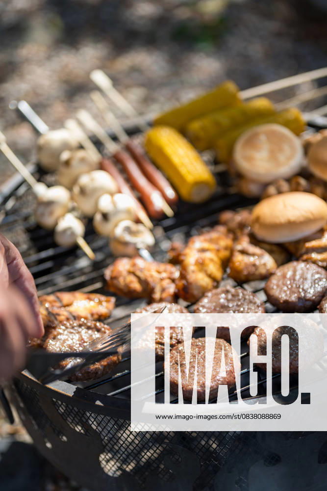 IMAGO Creative, Lifestyle, Feste im Garten #2 Grilled burgers, sausages and vegetables on barbecue in summer garden property released, IGEF00071