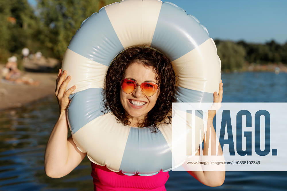 Curly woman smiling with life ring on lake model released, Symbolfoto, MCHF00682