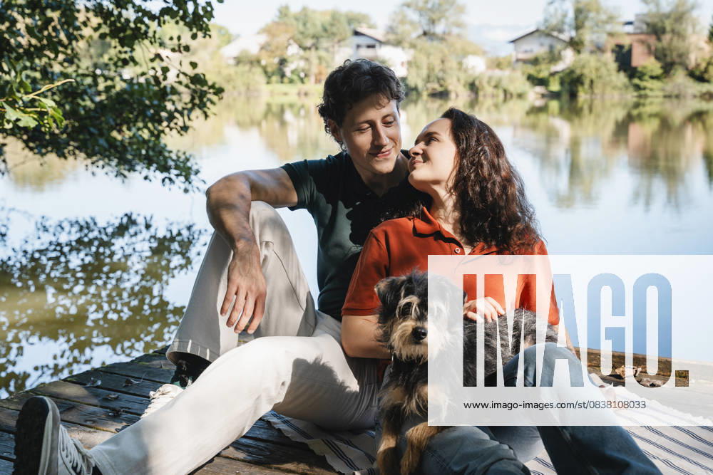 Couple with dog relaxing together outdoors by a lakeside in nature model released, Symbolfoto property released, NDEF02878