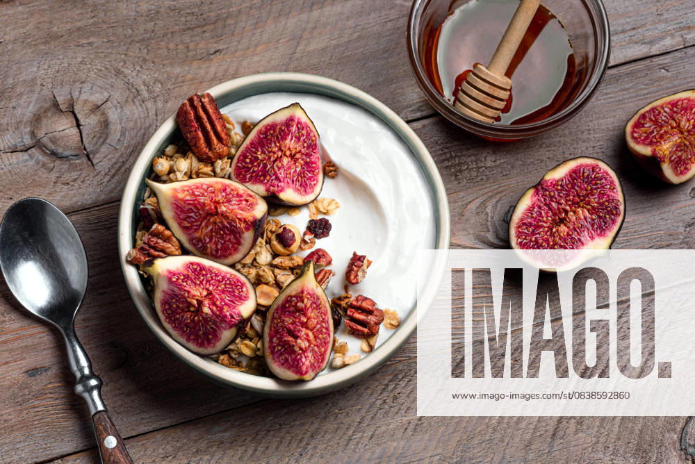 IMAGO Creative, Food, High Protein Frühstück Granola-Frühstücksbowl mit Feigen und Pekannüssen Granola bowl with figs and pecan nuts on wooden background, top view. Breakfast bowl with greek yogurt, granola, honey, fruits and nuts. (License=RF)