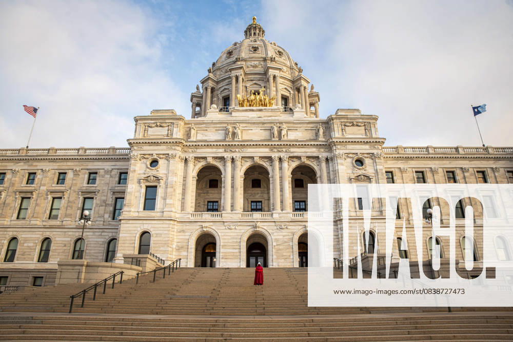 An activist dressed as a handmaiden from Margaret AtwoodÃ¢â‚¬â ¢s The HandmaidÃ¢â‚¬â ¢s Tale protests outside the Minnesota State Capitol. The flag of the United States flies on the left of the image; the state flag of Minnesota flies on the right of the image. Saint Paul United States - ZUMAp202 20251029_zip_p202_001
