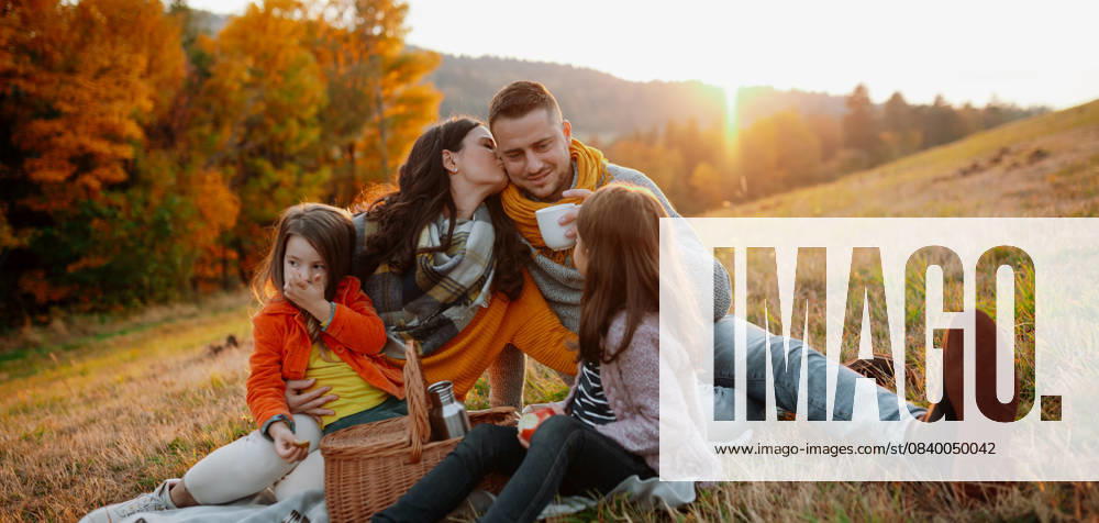 Parents with young children sitting outdoors in autumn light. Parents with young children sitting outdoors in autumn light, having picnic. model released