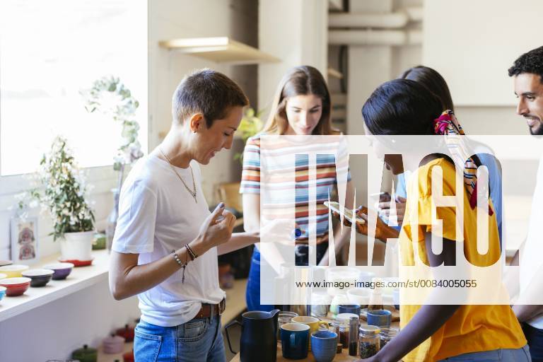 IMAGO Creative, Lifestyle, Leben in einer Wohngemeinschaft, WG Friends and instructor in a cooking workshop preparing a drink taking smartphone pictures model released Symbolfoto property released EBSF02471