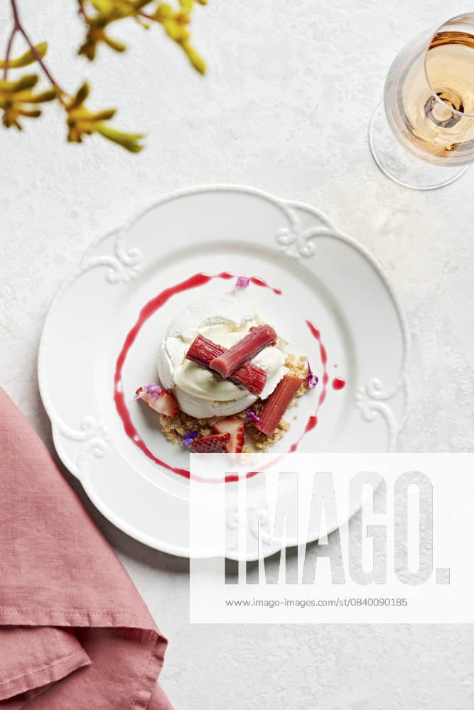 Individual pavlova on a vintage style plate with poached rhubarb, strawberries, lemon creme fraiche and crumble Individual pavlova on a vintage style plate with poached rhubarb, strawberries, lemon creme fraiche and crumble