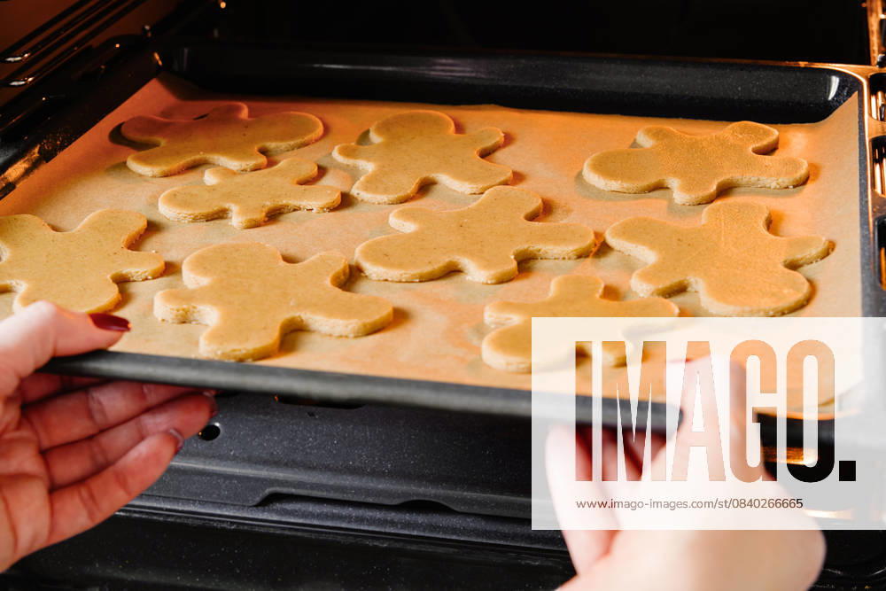 IMAGO Creative, Weihnachten, Food, Backen, Lebkuchen Weibliche Hände legt Backblech mit Weihnachten Lebkuchen Plätzchen Mann in den Ofen in der Küche. Weihnachten Backen Konzept Hintergrund. Female hands puts baking tray with Christmas gingerbread cookie man in oven in the kitchen. Christmas baking concept background. (License=RM)