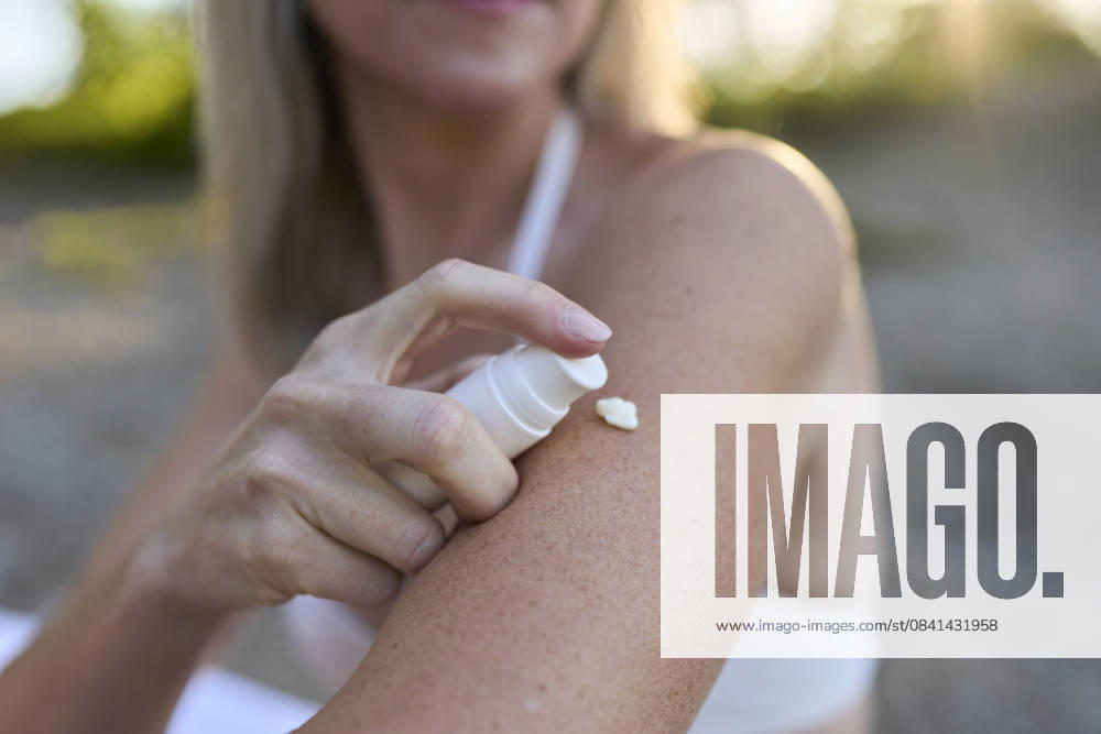 Woman applying sunscreen on arm outdoors in summer for skin care model released, Symbolfoto, PNEF03564