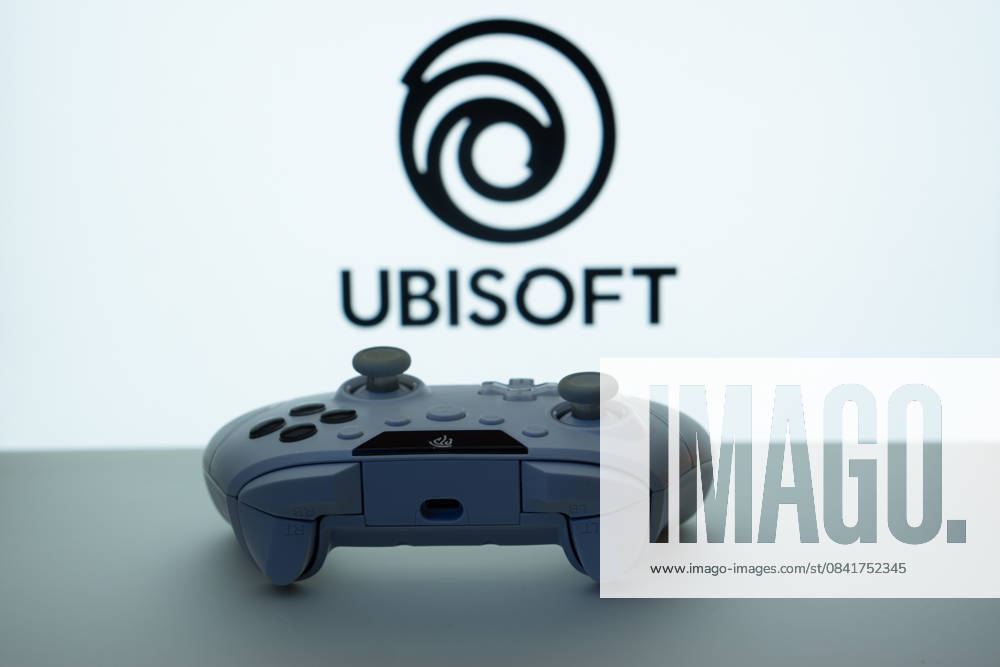 Dhaka, Bangladesch - 14. November 2025: Nahaufnahme eines weißen Gamepads mit dem Ubisoft-Schriftzug auf dem Bildschirm im Hintergrund. Dhaka, Bangladesh- 14 Nov 2025: A close-up of a white gamepad with the Ubisoft seen on screen in the background. (License=RM)