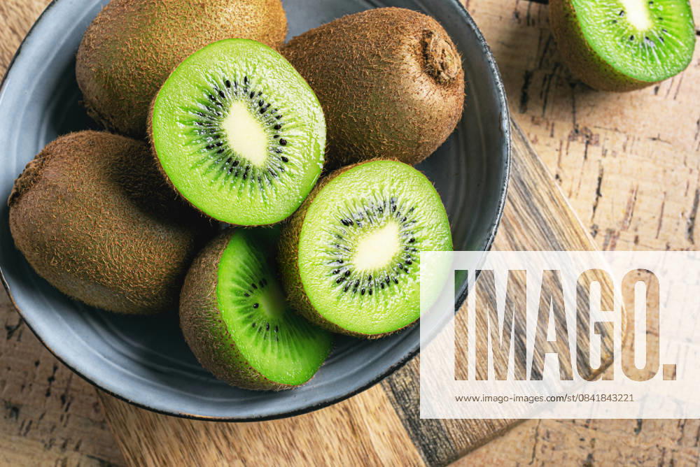 Kiwi-Früchte in Holzschale Kiwi fruits in wooden bowl. Whole fruit and half pieces of green kiwi close up. Fresh ripe kiwi. Organic healthy eating template. (License=RF)