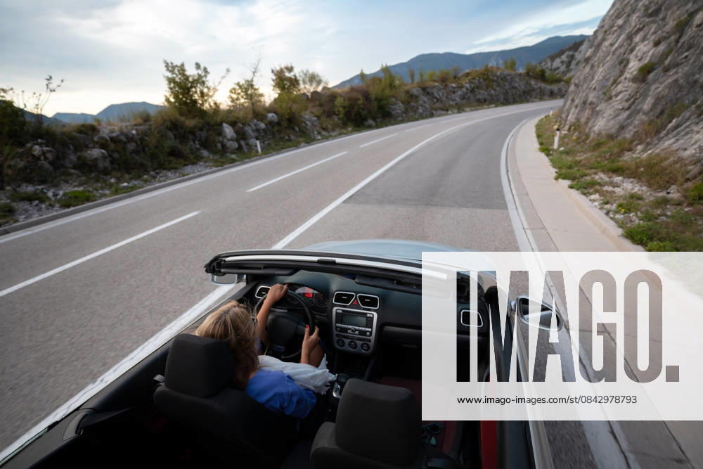 Junge Frau fährt Cabrio entlang der malerischen Meeresküste und der Bergstraße bei Sonnenuntergang, unbeschwerter Sommerurlaub, Reisefreiheit und Abenteuer auf der Küstenautobahn Junge Frau fährt Cabrio entlang der malerischen Meeresküste und der Bergstraße bei Sonnenuntergang, unbeschwerter Sommerurlaub, Reisefreiheit und Abenteuer auf der Küstenautobahn (License=RF) ,model released, Symbolfoto