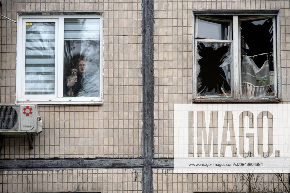 A woman holding a dog looks out of a surviving window in a five-storey residential building damaged by a Russian drone attack in the Sviatoshynskyi district of Kyiv, Ukraine, December 23, 2025. Falling Russian drone debris partially destroyed the roof and facade of the apartment block. Five people, including a child, were injured in the attack. (Photo by Danylo Antoniuk Ukrinform) Russian drone debris falls on apartment block in Kyiv