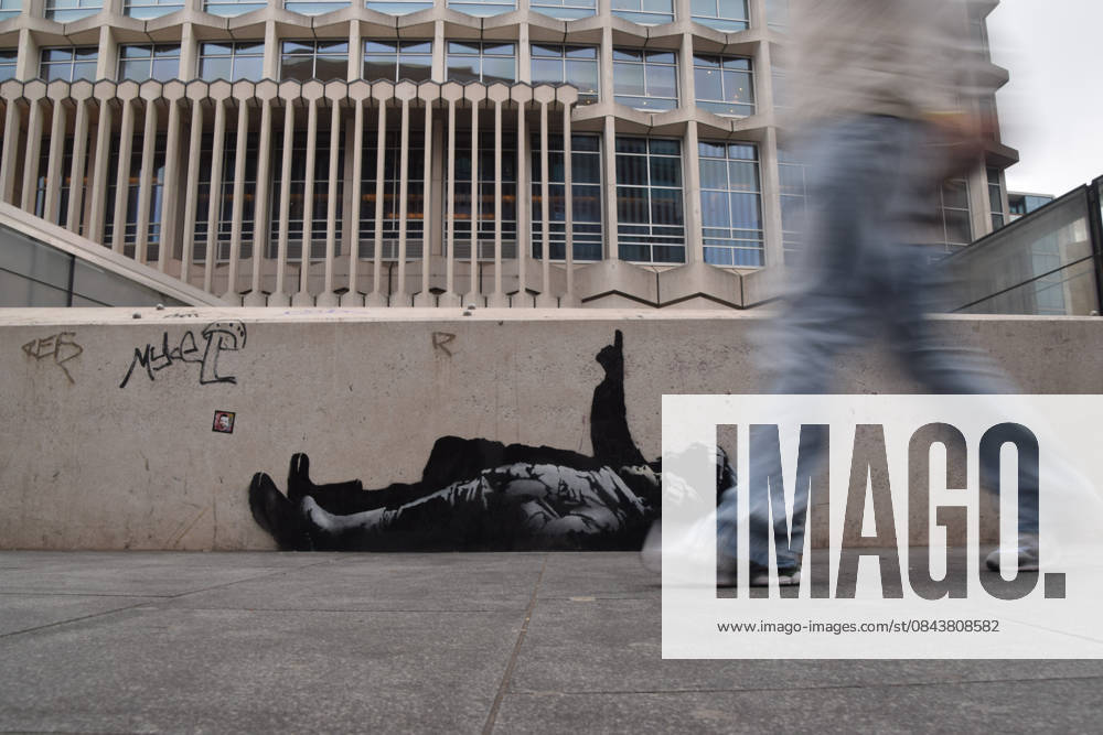 A person walks past the new Banksy artwork on a wall outside Centre Point and Tottenham Court Road station. Two identical new artworks, one of which has now been confirmed by elusive street artist Banksy, have appeared outside Centre Point and on an unoccupied mews building in Bayswater. The artworks depict two children lying on their backs and one child pointing upwards. London United Kingdom - ZUMAs197 20251223_aab_s197_032