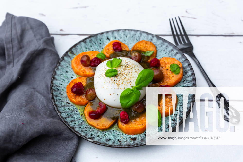 Burrata with sweet potato, pesto, cranberries, grapes, and basil on plate, SARF04689