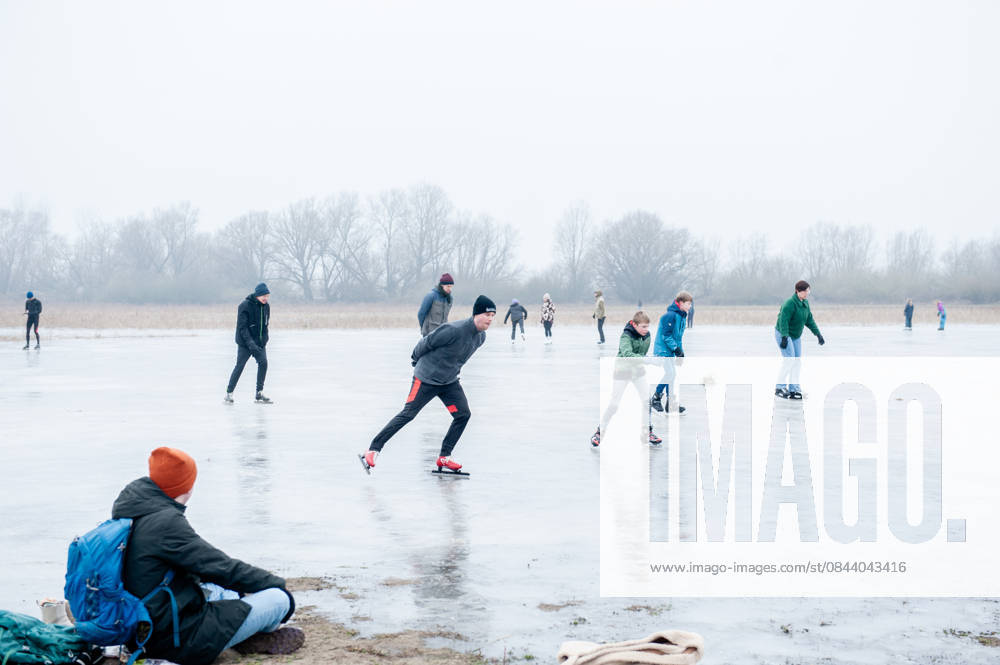 A man observes people skating on the freezing lake. After several days of sub-zero temperatures during the night, the water of some lakes started to freeze over. People took the chance to skate on one of the frozen lakes close to the Dutch city of Nijmegen. It takes at least four whole days of below-freezing temperatures to form ice thats safe to walk and skate on, and that only applies to ponds or lakes with no currents. Nijmegen Netherlands - ZUMAs197 20251227_aab_s197_058